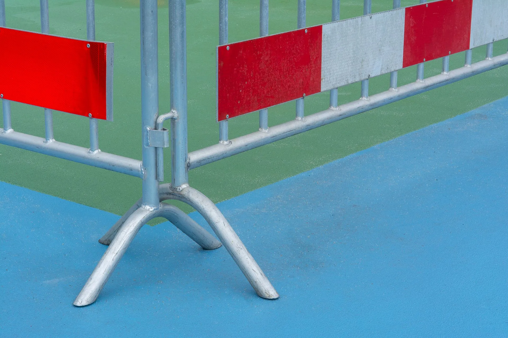 Close-up of temporary steel barrier fence panels with red and white reflective panels and stand