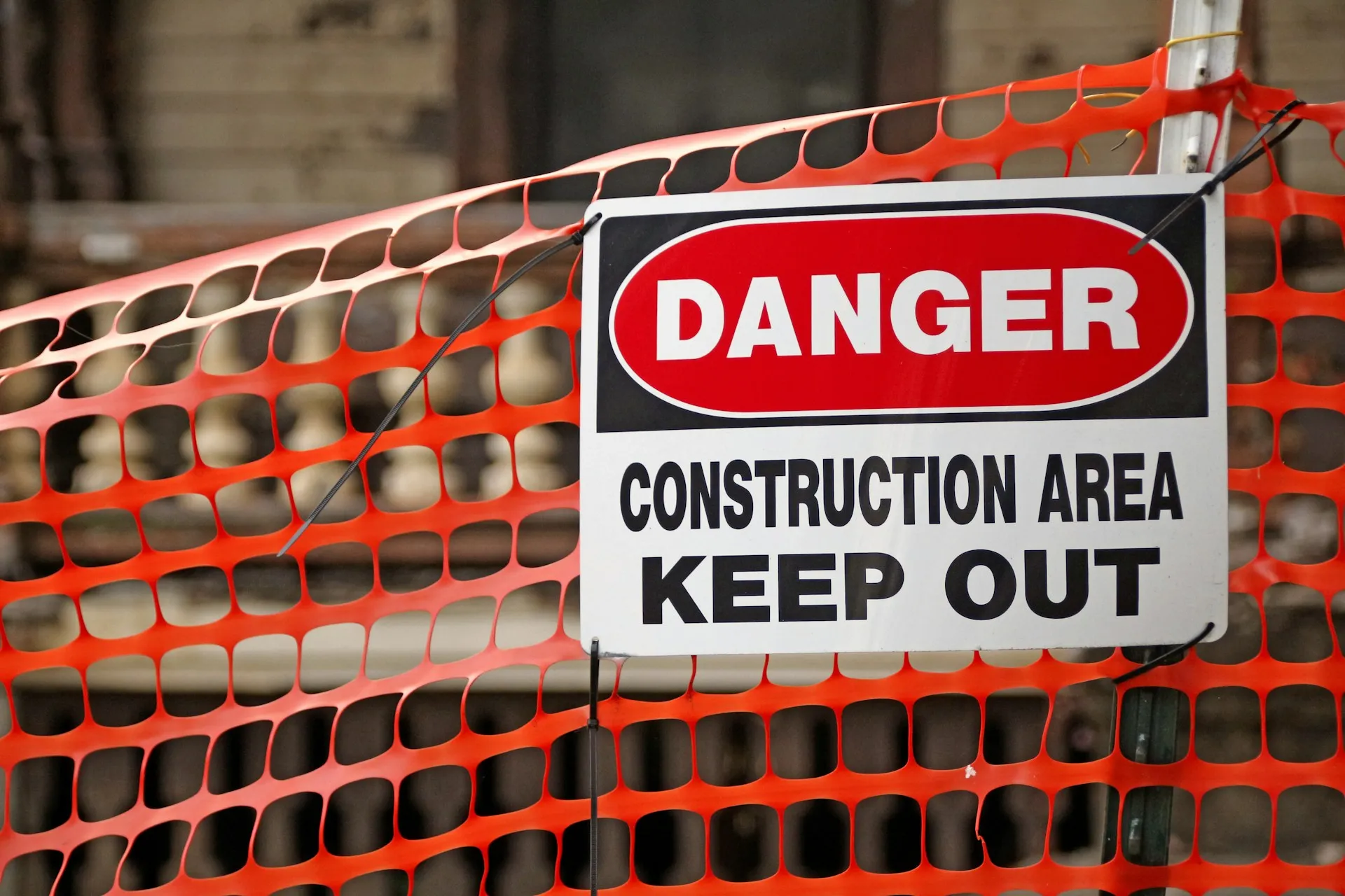 Orange temporary safety fence with a danger construction area keep out sign